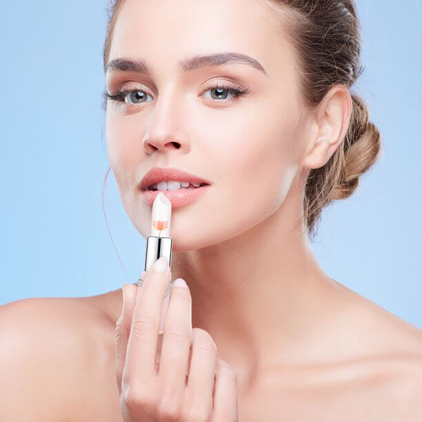 Frau trägt transparenten Lippenstift auf, Beauty-Make-up, natürliche Lippenpflege, blauer Hintergrund.