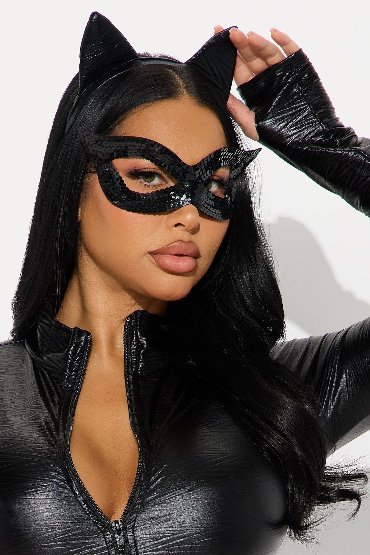 Porträttbild där modellen lyfter ena kattörat och visar den svarta paljettmasken med tummhål i ärmen 3