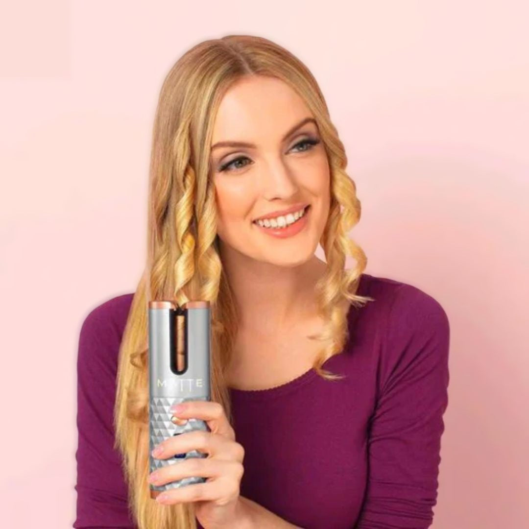 Frau mit automatischem Lockenstab, blondes Haar, lila Oberteil, Haarstyling, Lockenfrisur.