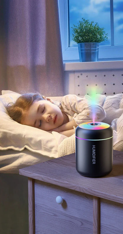 Schlafendes Kind neben LED-Luftbefeuchter, schwarz, auf Holztisch, Nacht, Schlafzimmer.