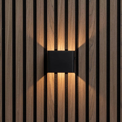 Svart vägglampa rakt framifrån på träpanel, varmt ljus uppåt och nedåt 5