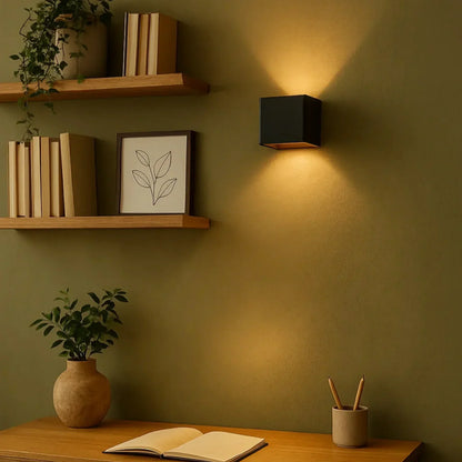 Svart vägglampa på grön vägg bredvid hyllor, skrivbord och en uppslagen bok 9