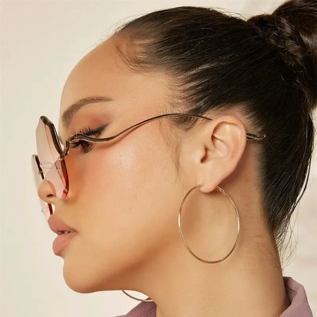Frau mit luxuriöser Sonnenbrille, Farbverlaufsgläser, goldene Creolen, modisches Accessoire.