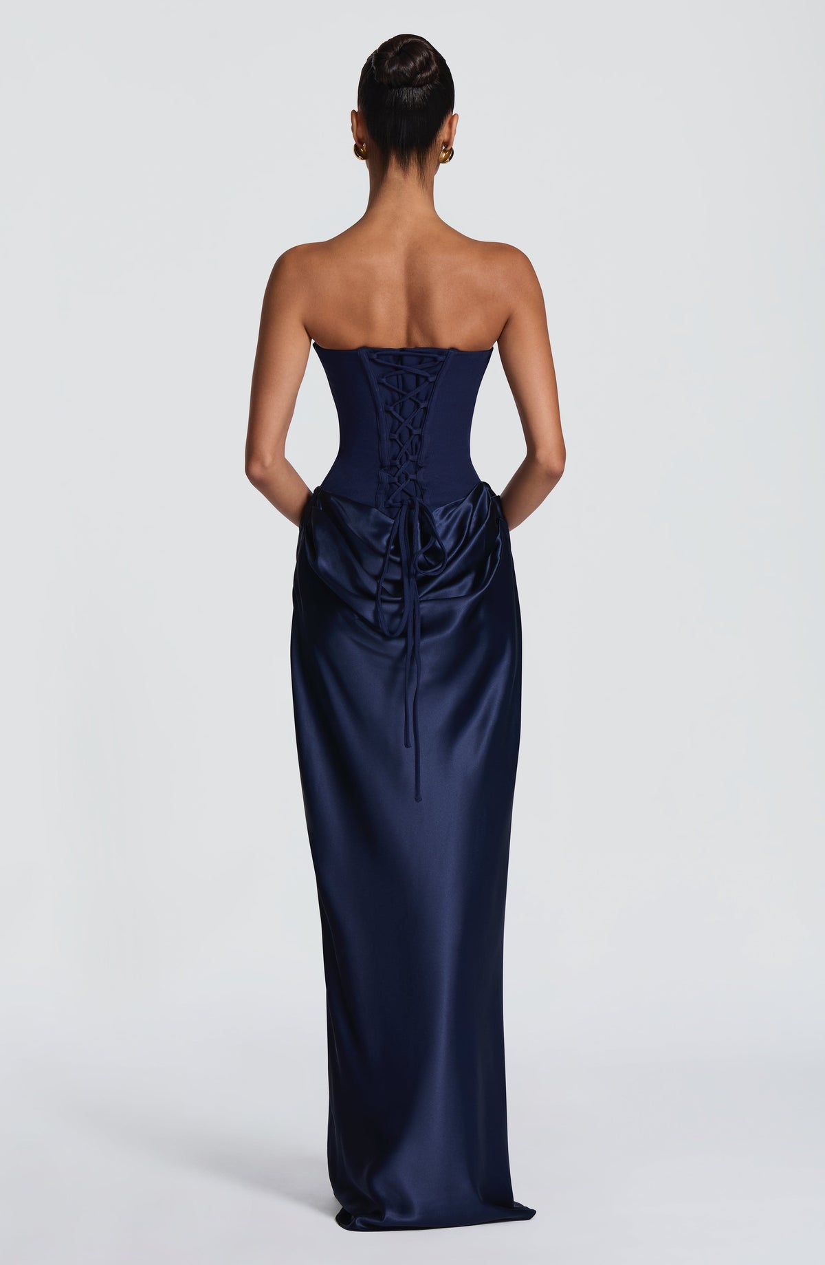 Klänningens ryggsida i marinblått med snörning i korsettlivet och draperad satängkjol, modellen sedd bakifrån 44