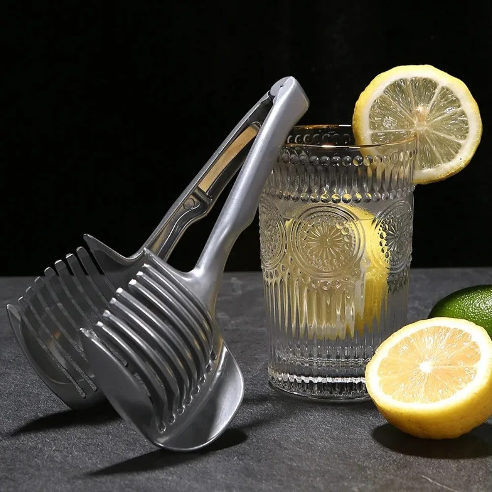 Metallischer Spaghettilöffel neben Glas mit Zitronenscheiben, Küchengerät, Edelstahl.