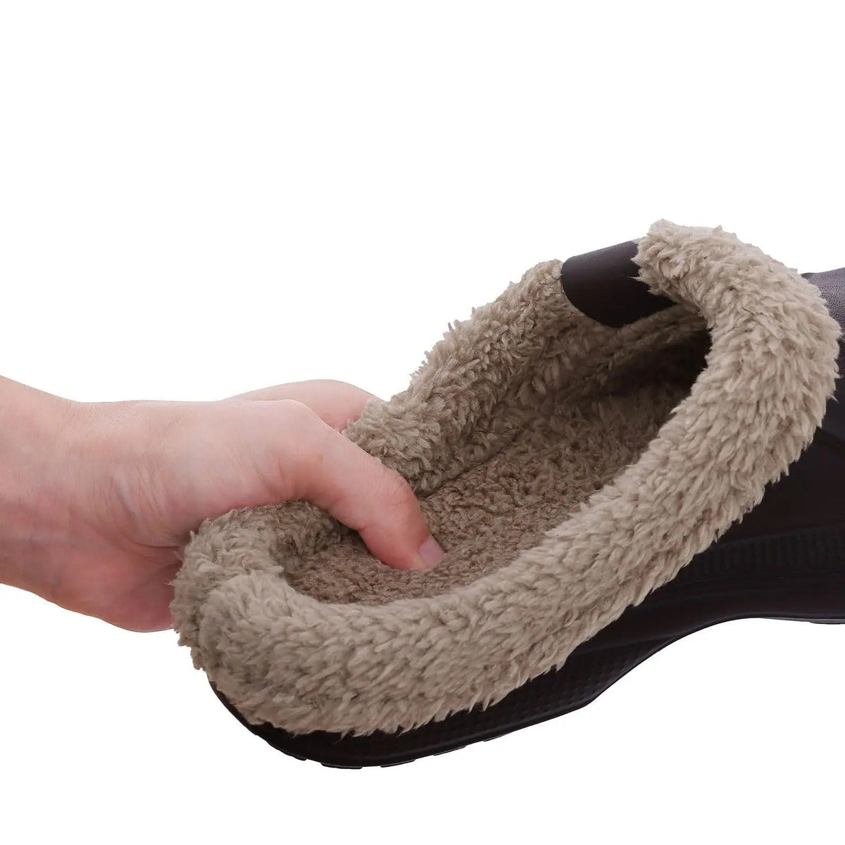 En hand trycker mot det mjuka beigea pälsfodret inuti en mörk toffel, som visar fodrets tjocklek. 5