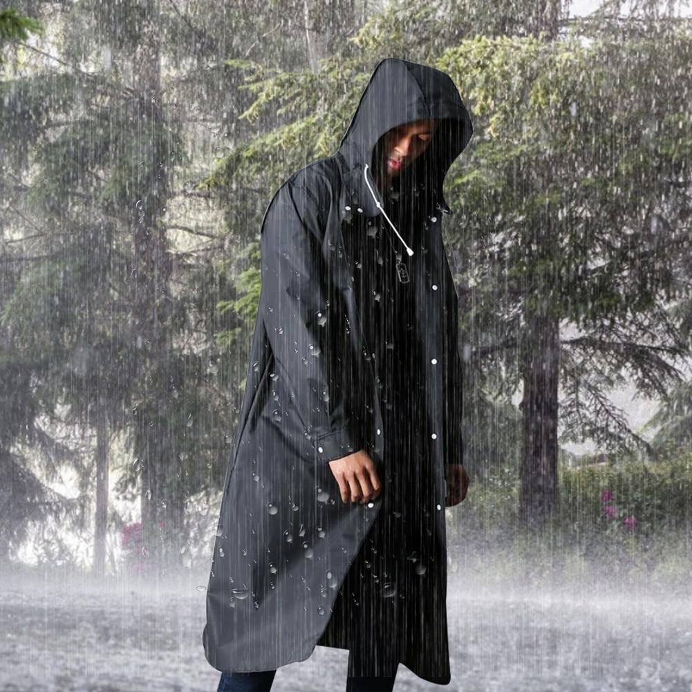 Mann in schwarzem Regenmantel im Wald bei Regenwetter, wasserdicht, Outdoor-Bekleidung.