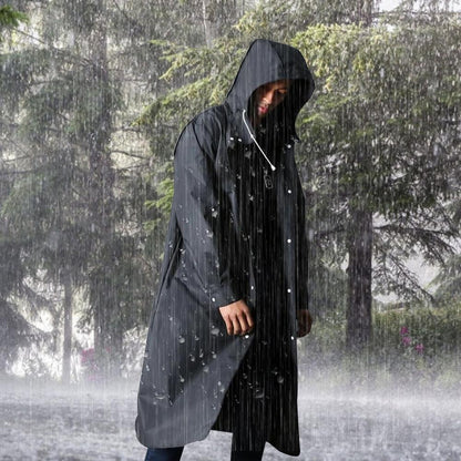 Mann in schwarzem Regenmantel im Wald bei Regenwetter, wasserdicht, Outdoor-Bekleidung.