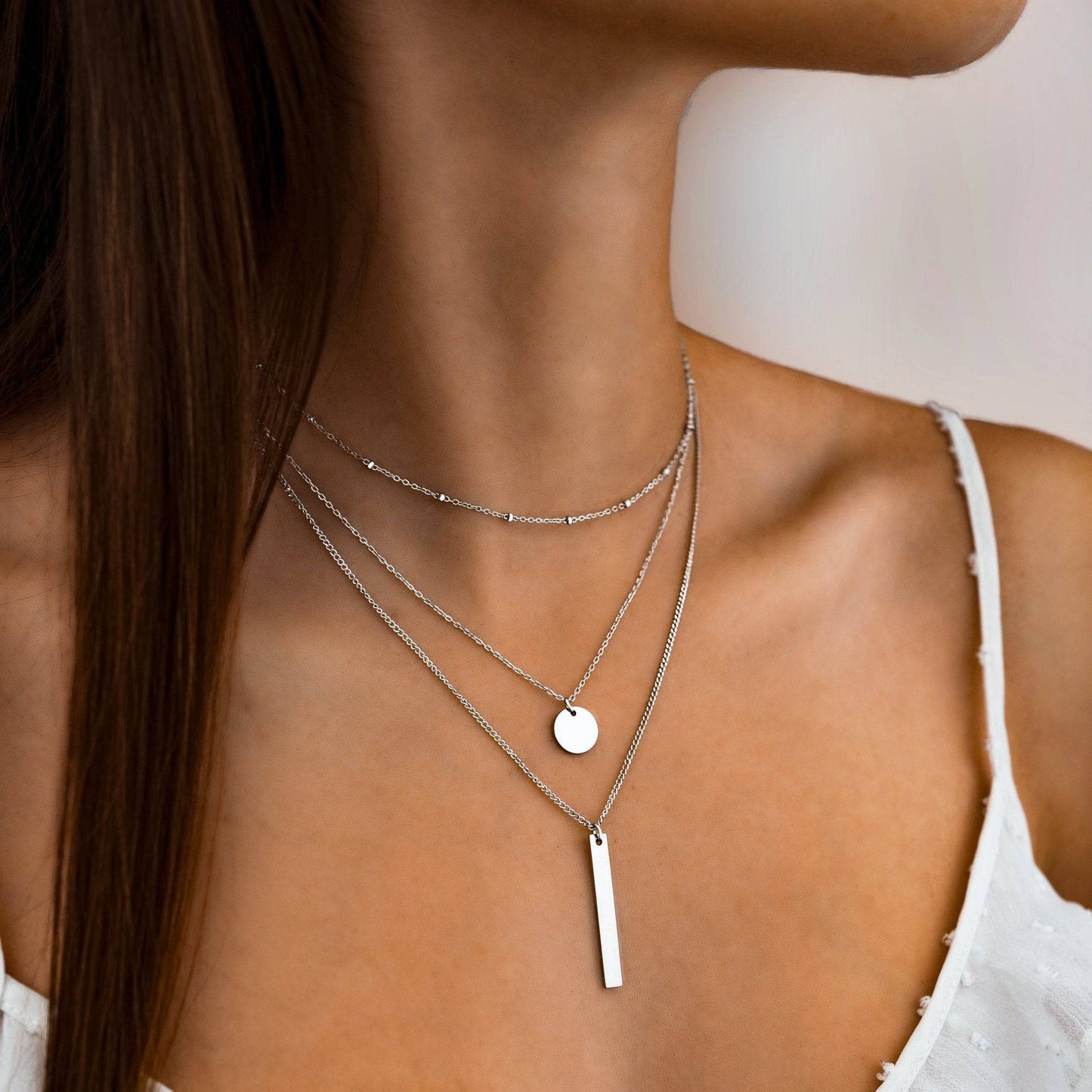 Frau trägt silberne Halskette mit Anhänger, minimalistischer Schmuck, elegantes Design.