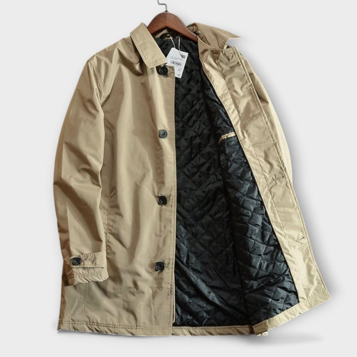 Beige kappa på galge, framifrån med öppen front som visar det svarta quiltade fodret och svarta knappar. 7