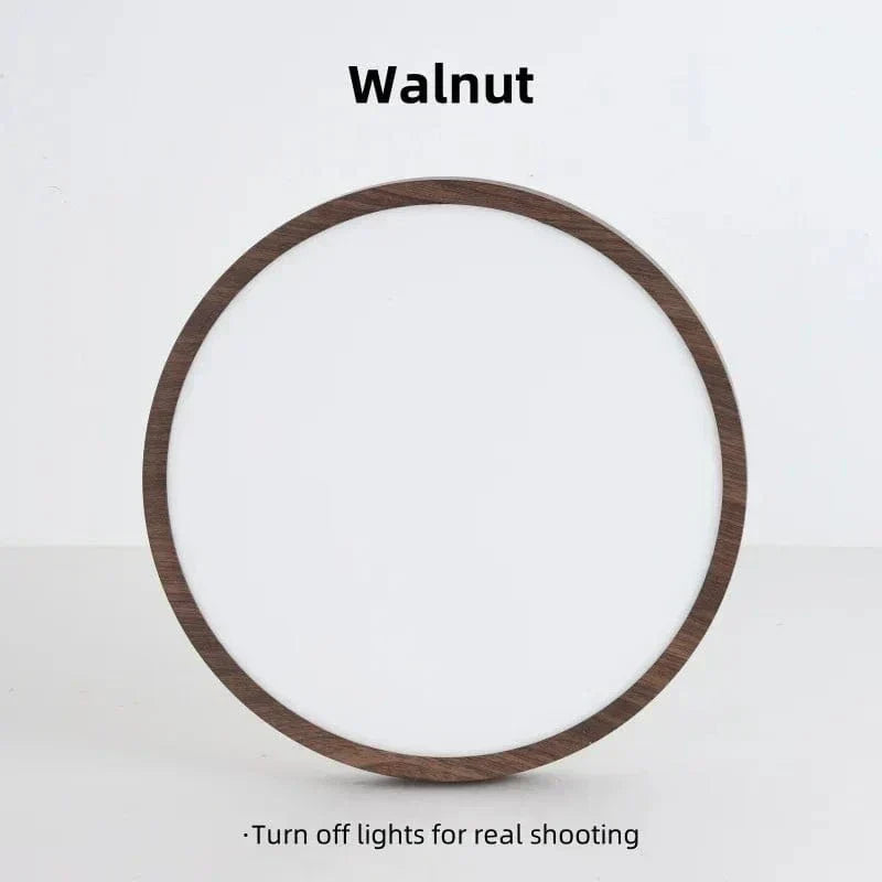 Släckt rund lampa med mörk valnötsfinish sedd rakt framifrån mot en ljus bakgrund. 17