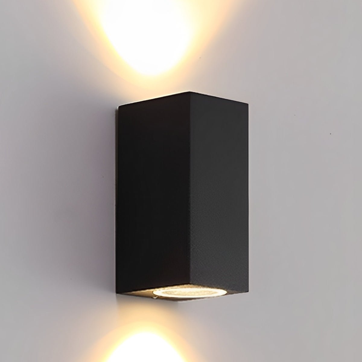 Svart rektangulär vägglampa som lyser både uppåt och nedåt på en ljus vägg 3