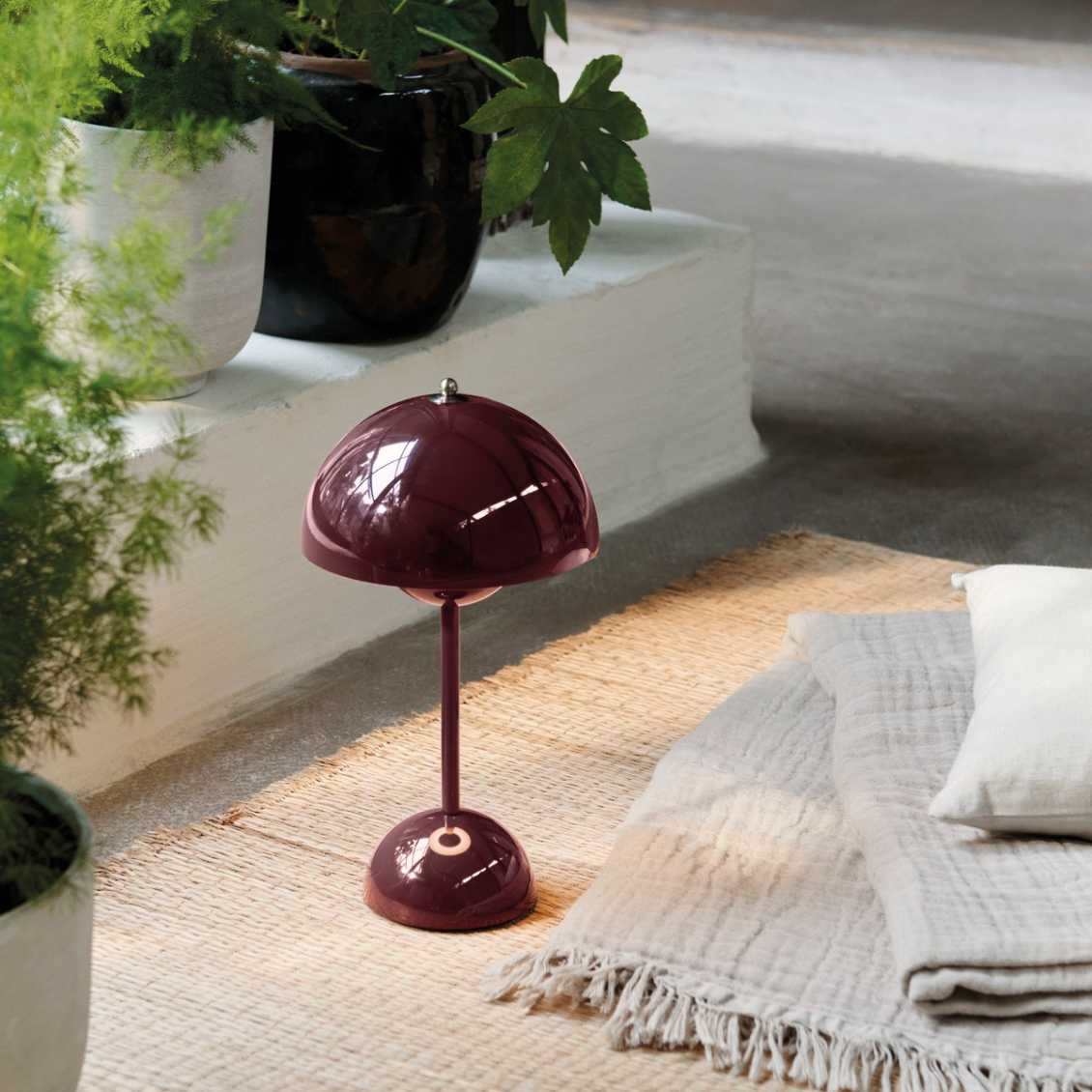 Bordeauxfarbene Tischlampe auf Teppich, modernes Design, Wohnzimmerdekoration, skandinavisch.