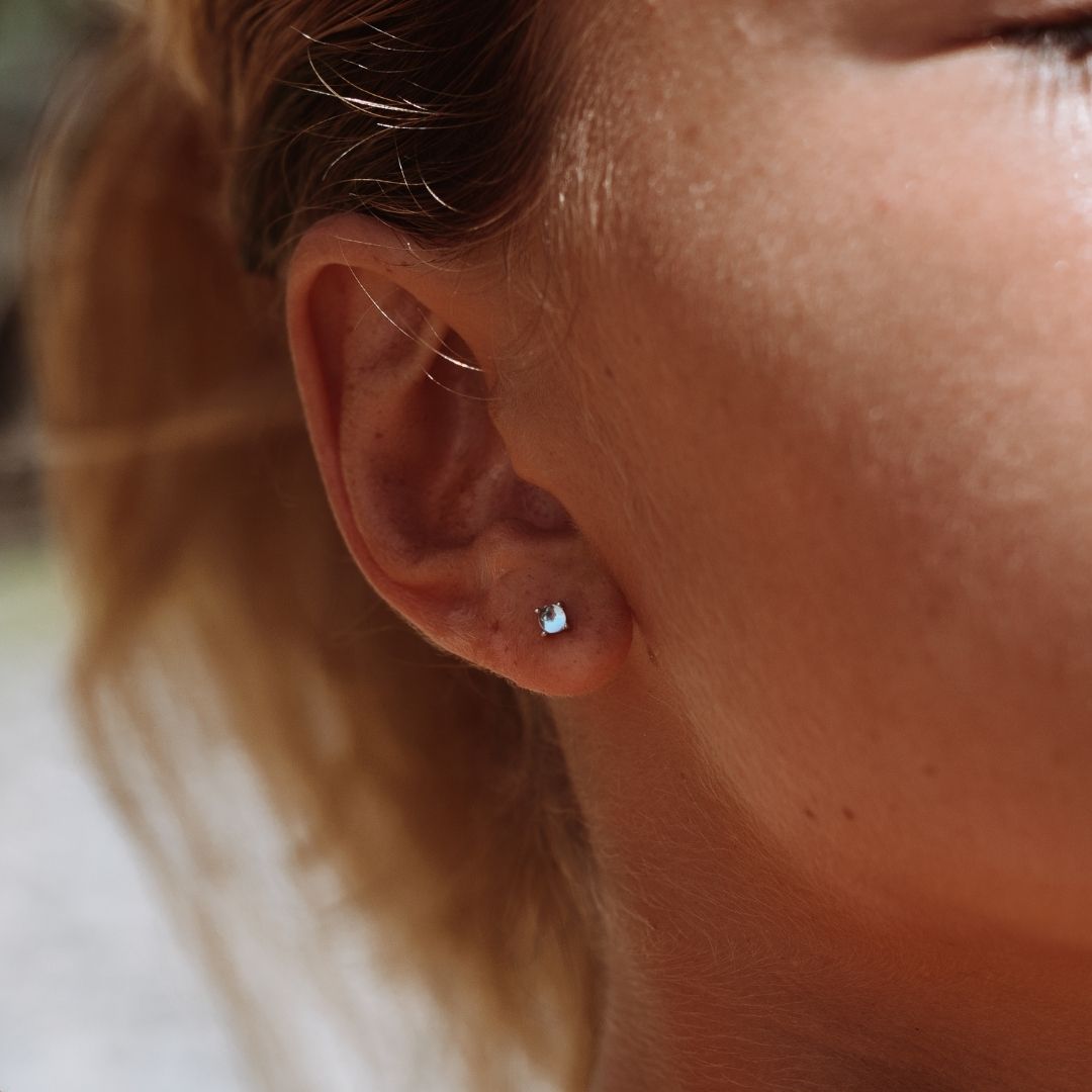 Nahaufnahme Ohr mit silbernem Perlenohrring, eleganter Schmuck, Damenaccessoire.