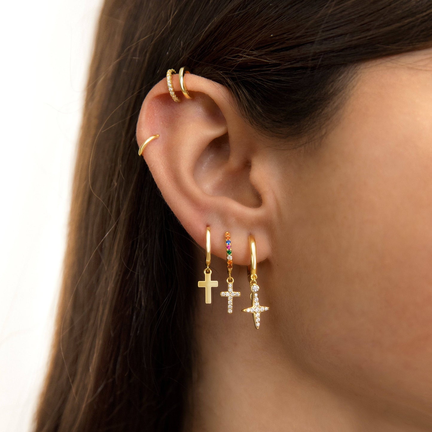 Frau mit goldenen Ohrringen und Ohrmanschetten, Kreuzanhänger, modischer Schmuck.