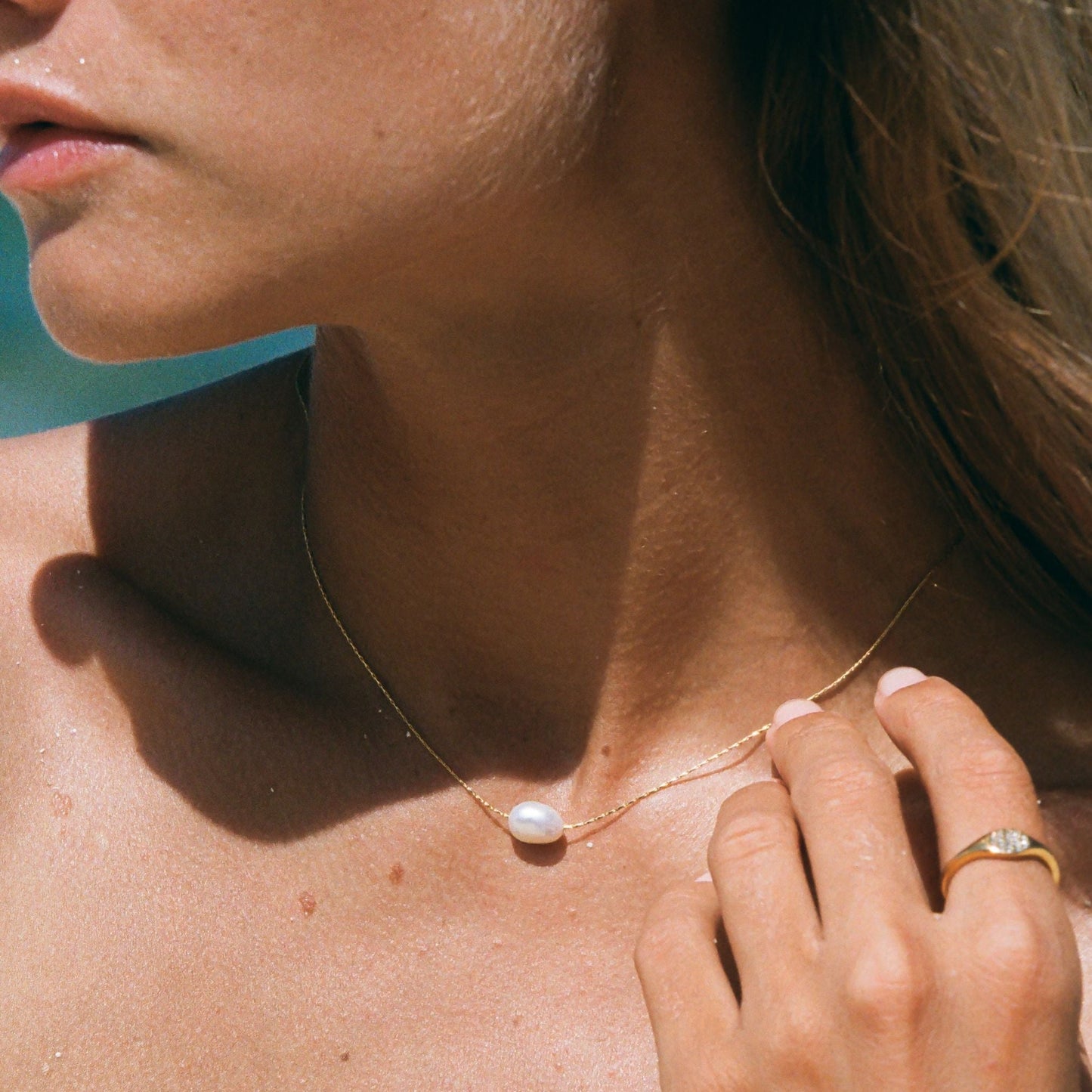 Frau mit goldener Perlenkette, eleganter Schmuck, minimalistisch, Sommermode, Nahaufnahme.