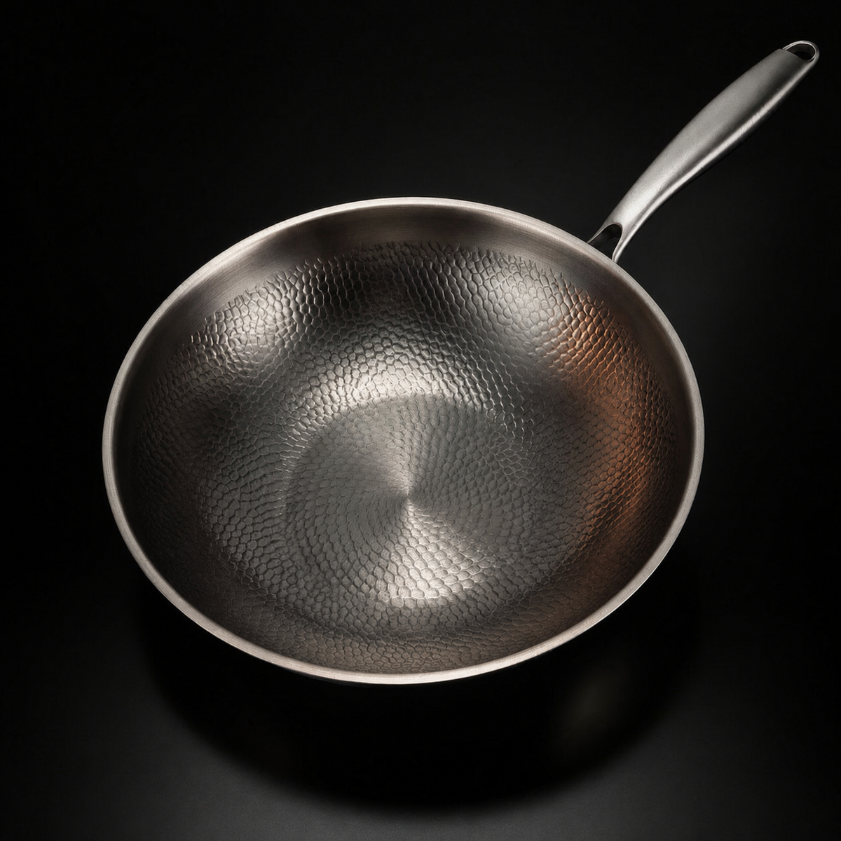 Wokpannan snett ovanifrån, med den hamrade, fjällika ytan i botten och på sidorna tydligt synlig. 2