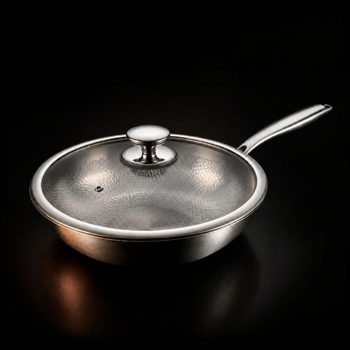 Wokpannan med glaslocket på, fotograferad snett från sidan mot svart bakgrund, med blank kant och mönstrad insida synlig genom glaset. 4