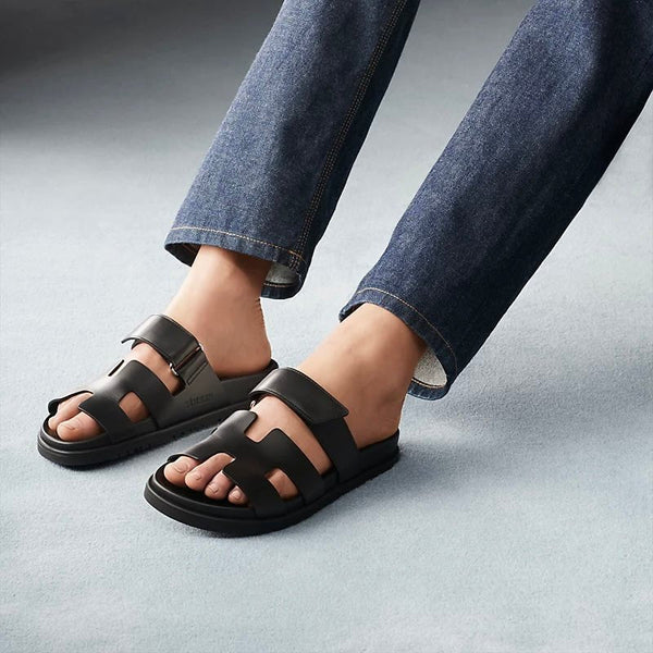 Schwarze Ledersandalen, Herren, lässig, bequem, mit Jeans, auf Teppichboden.