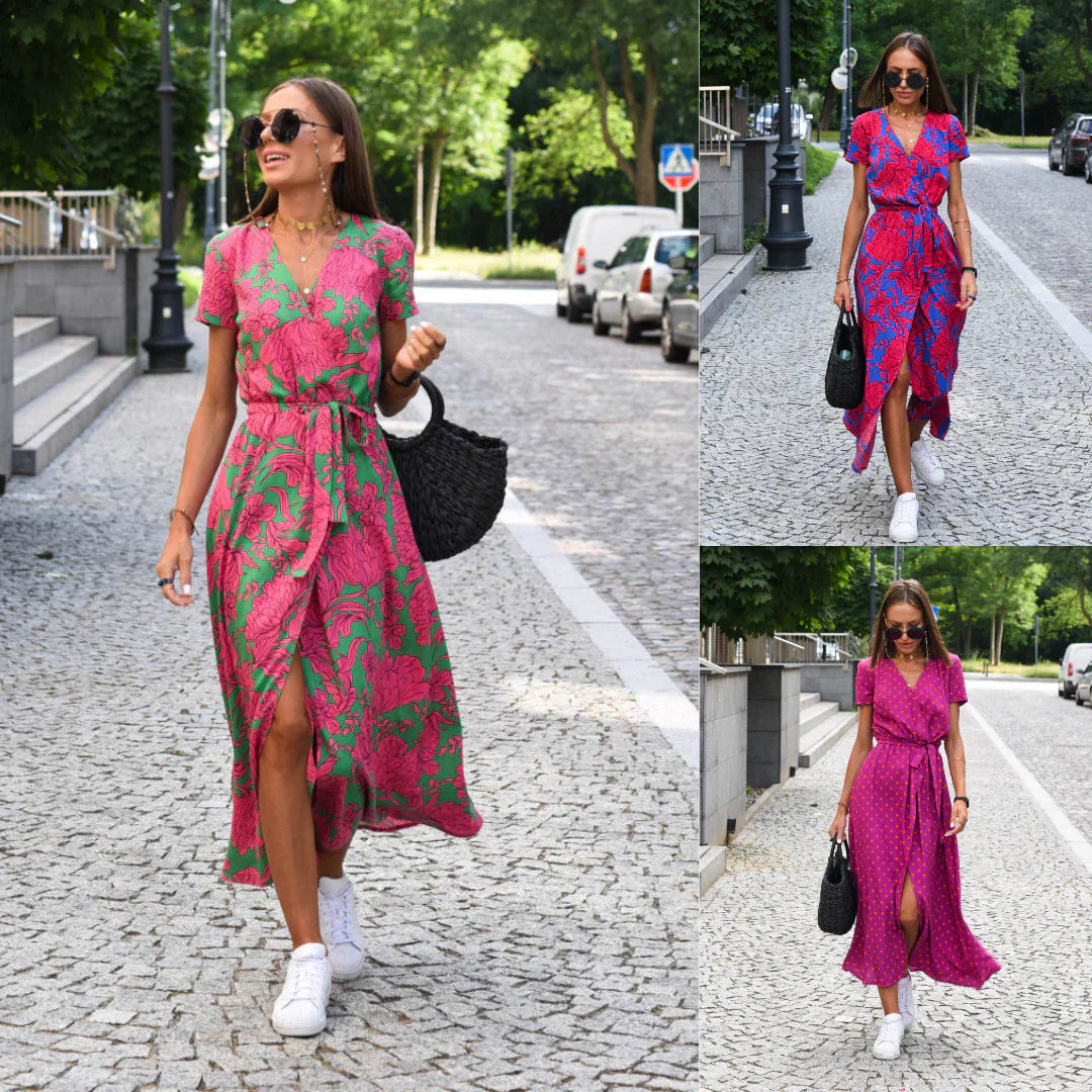 Frau in pink-grünem Sommerkleid, trägt schwarze Tasche, weiße Sneaker, läuft auf Kopfsteinpflaster.