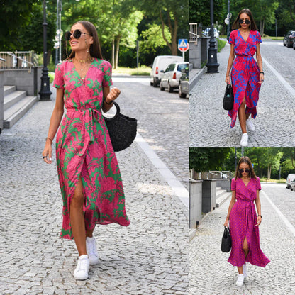 Frau in pink-grünem Sommerkleid, trägt schwarze Tasche, weiße Sneaker, läuft auf Kopfsteinpflaster.