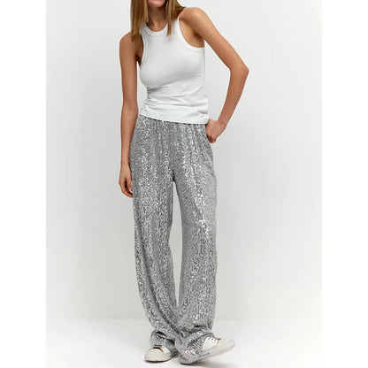 Frau trägt silberne Paillettenhose, weißes Tanktop, lässiger Look, modisch, elegant.