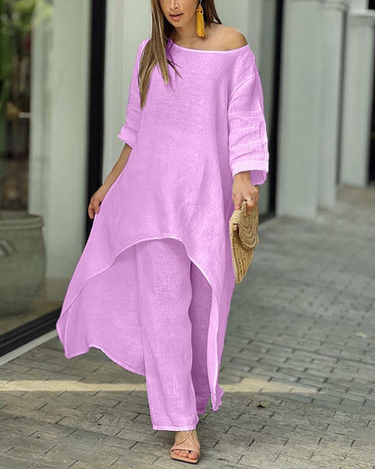 Frau in rosa Leinenkleid, asymmetrisch, mit Strohtasche, Sommermode, draußen.