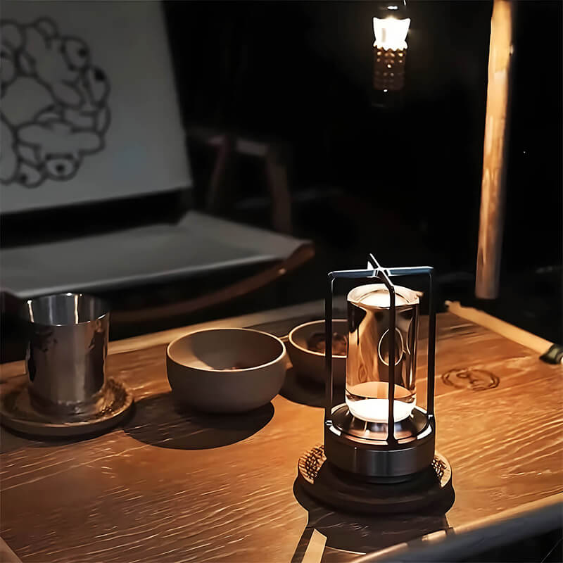 Moderne Tischlampe aus Metall auf Holztisch, umgeben von Keramikschalen und Metallbecher.
