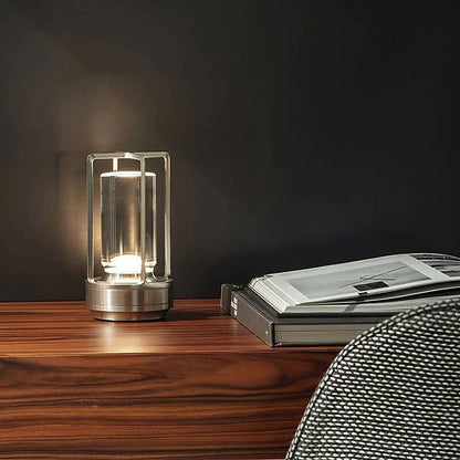 Moderne Tischlampe aus Metall auf Holztisch, neben offenem Buch, stilvolle Beleuchtung.