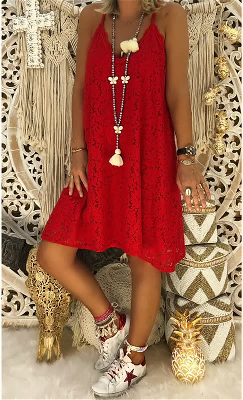 Frau in rotem Spitzenkleid, Boho-Stil, mit langen Halsketten, vor dekorativem Hintergrund.