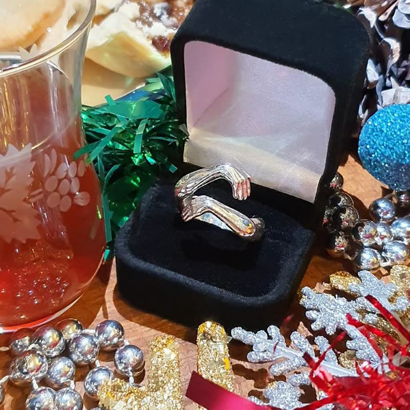 Silberner Ring in schwarzer Schmuckschatulle, umgeben von Weihnachtsdekorationen.