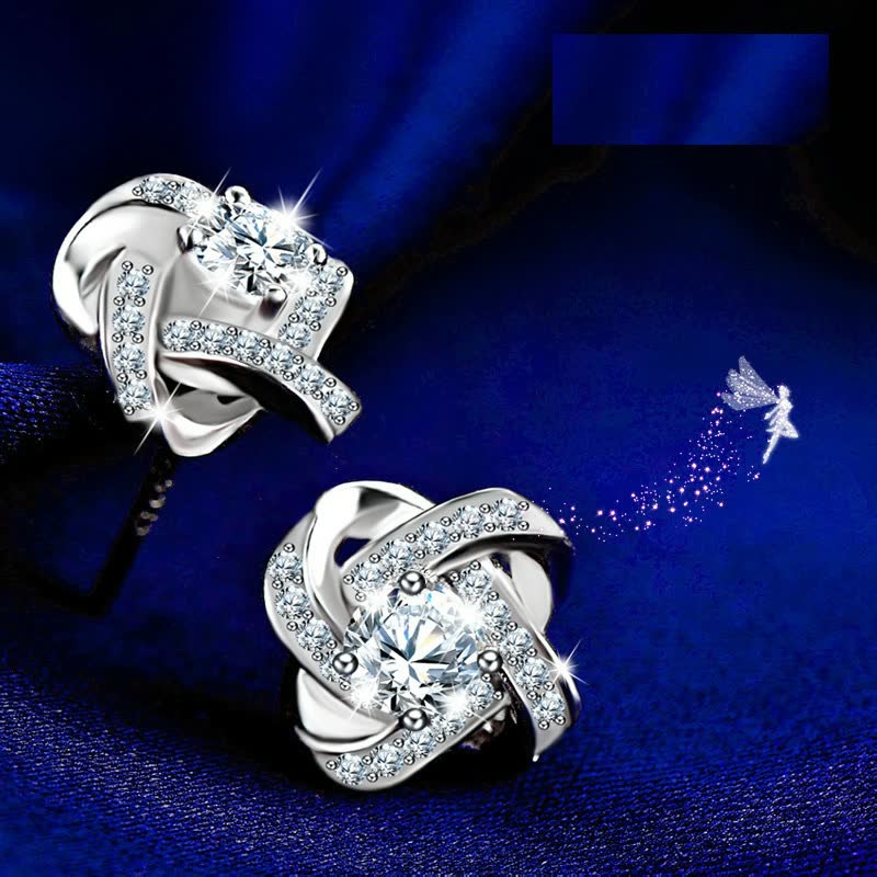 Silberne Ohrringe mit Zirkonia, funkelnd, auf blauem Hintergrund, eleganter Schmuck.