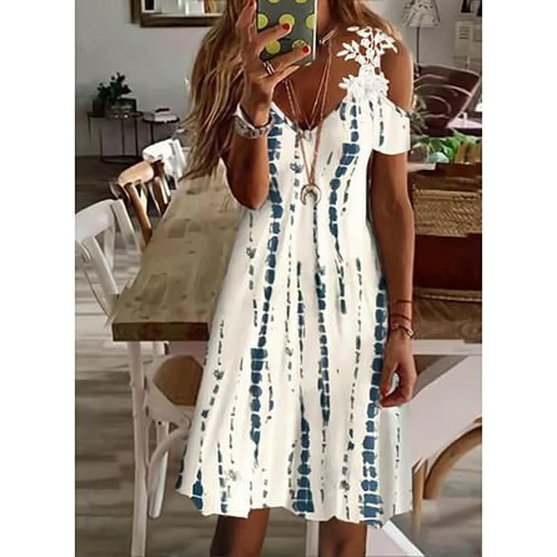 Frau in weißem Sommerkleid mit blauem Muster, schulterfrei, in modernem Esszimmer.