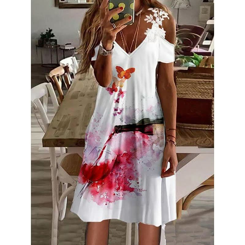 Frau in weißem Sommerkleid mit Weinglas- und Schmetterlingsmotiv, lässige Mode.