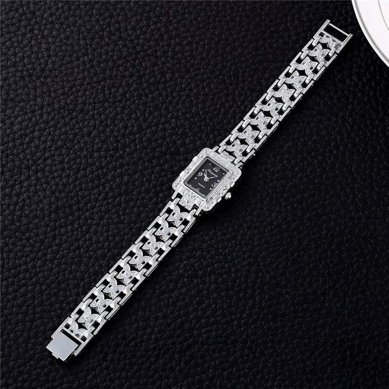 Luxus-Damenuhr mit silbernem Armband und schwarzem Zifferblatt auf schwarzem Hintergrund.