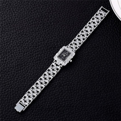 Luxus-Damenuhr mit silbernem Armband und schwarzem Zifferblatt auf schwarzem Hintergrund.