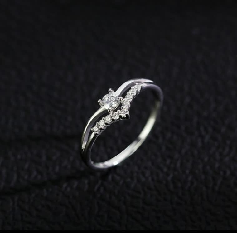 Silberner Diamantring mit geschwungenem Design auf schwarzem Hintergrund, eleganter Schmuck.