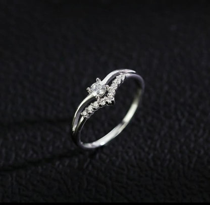 Silberner Diamantring mit geschwungenem Design auf schwarzem Hintergrund, eleganter Schmuck.