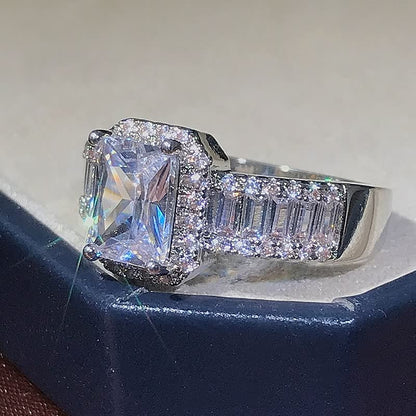 Silberner Verlobungsring mit quadratischem Diamant und Pavé-Fassung, funkelnd, elegant.
