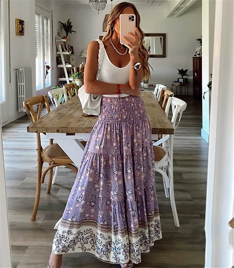 Frau in weißem Top und lila Maxirock mit Blumenmuster, steht in modernem Esszimmer.