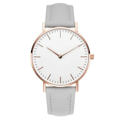 Minimalistische Armbanduhr mit weißem Zifferblatt, roségoldenem Gehäuse und grauem Lederarmband.