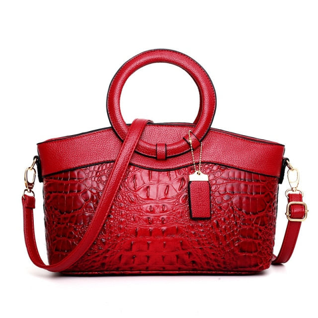 Rote Damenhandtasche aus Leder mit Krokodilprägung und rundem Griff, modisch und elegant.