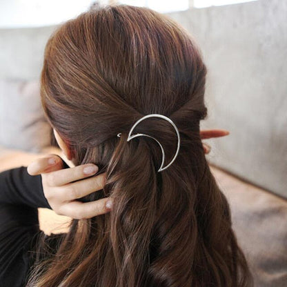 Frau mit braunem Haar trägt silberne Mond-Haarspange, modisches Accessoire, eleganter Stil.