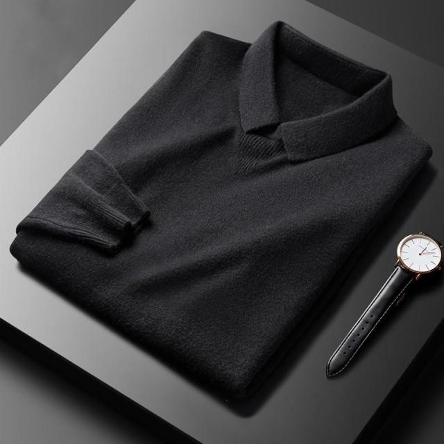 Schwarzer Herrenpullover aus Kaschmir, gefaltet, neben einer eleganten Armbanduhr auf schwarzem Tisch.