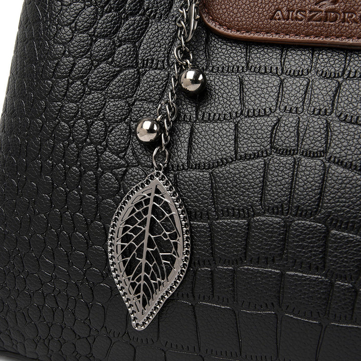 Schwarze Krokodilleder-Handtasche mit Blattanhänger, Damenmode, elegantes Design.
