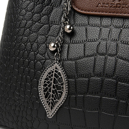 Schwarze Krokodilleder-Handtasche mit Blattanhänger, Damenmode, elegantes Design.