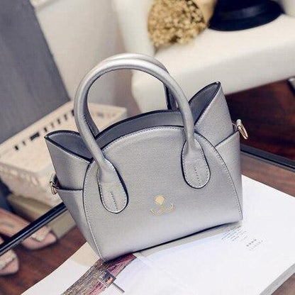 Silberne Damenhandtasche aus Leder auf Glastisch, elegantes Design, modisches Accessoire.