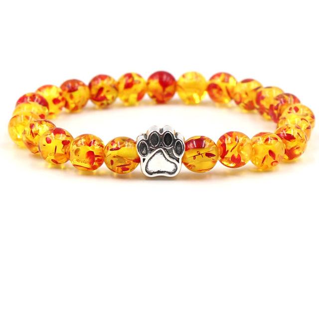 Gelbes und rotes Perlenarmband mit silbernem Pfotenanhänger, modisches Schmuckstück.
