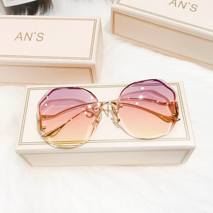 Lila-rosa Sonnenbrille mit goldenen Bügeln auf weißer Box, modisches Accessoire.