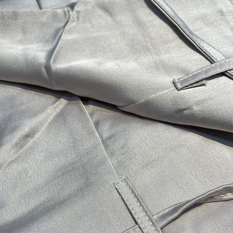 Seidener Stoff in Silber, glänzend, luxuriös, für Mode und Dekoration, Nahaufnahme.
